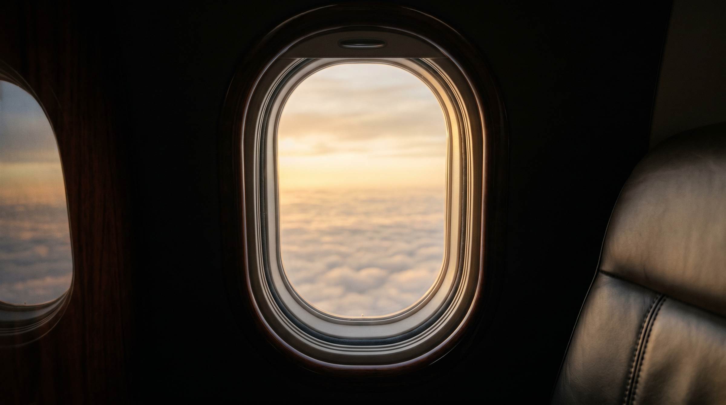 View through a private jet window of a golden sunset above the clouds